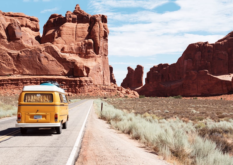 Yellow van driving toward red rock formations