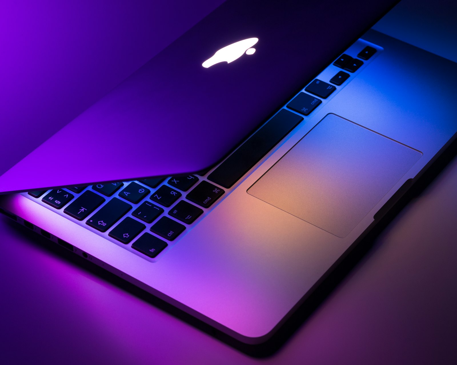 Silver MacBook half open against a neutral studio backdrop