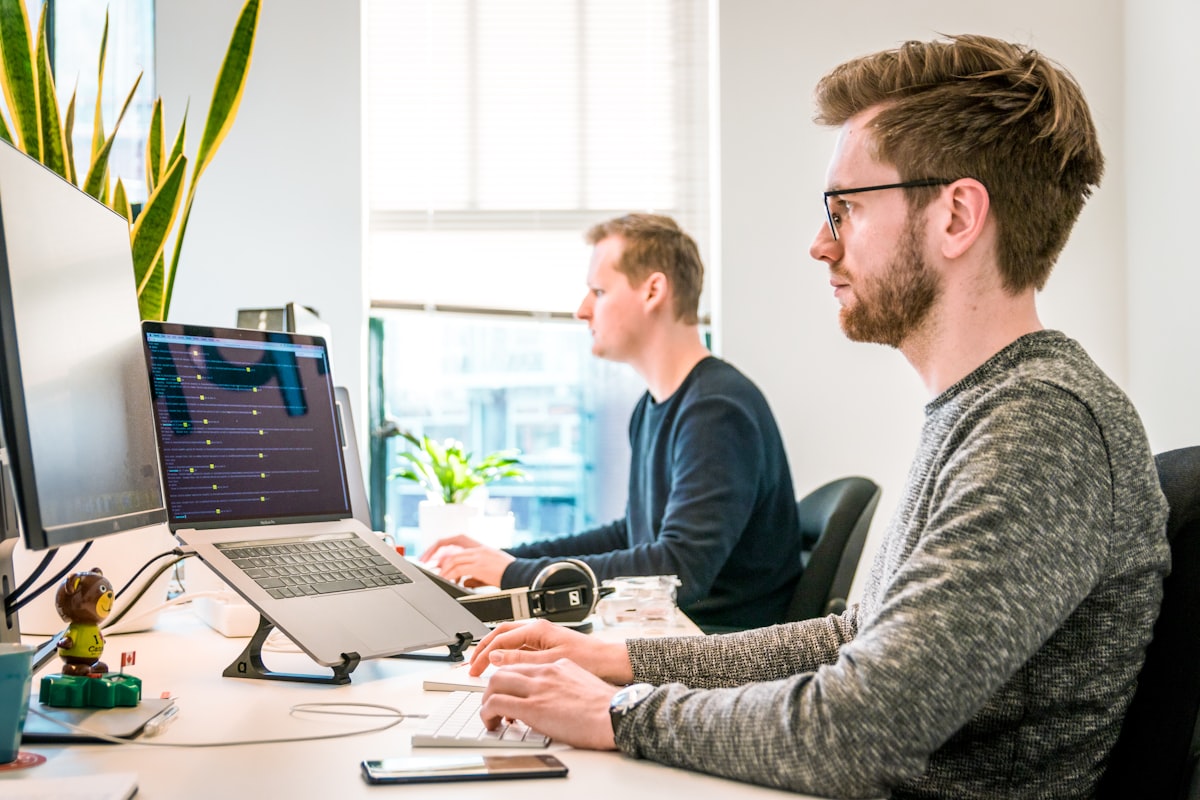 Two developers working at a desk with large monitors